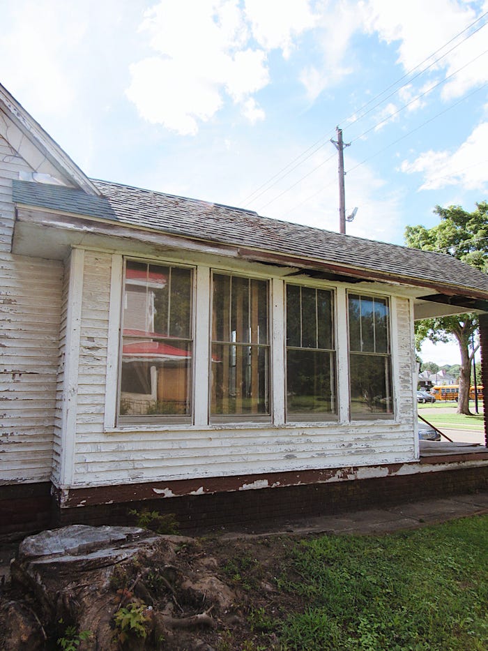 A side of the house with worn-out siding and dirty windows